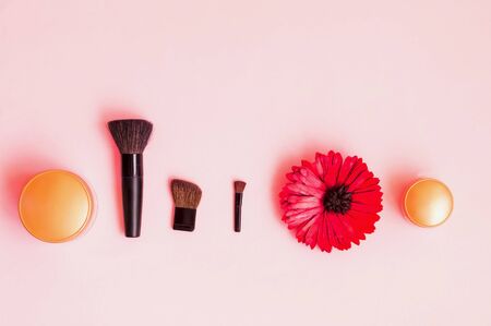Festive background for decorative cosmetics. Cosmetic brushes and shadows on pastel pink background....