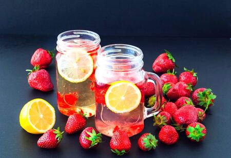 Cold drinks from strawberries and lemon in glass cups on a dark background. The concept of natural products.Copy space Close-up, top view.の写真素材