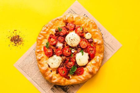Homemade pizza on the texture of old newspaper on bright yellow background. The concept of traditional Italian food. Close-up, copy spaceの写真素材