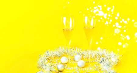 Brilliant Christmas decor. Filled glasses and bottle of champagne decorated in festive theme on yellow background. Close-up, copy spaceの写真素材