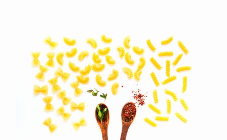 Wooden spoons with spices and pasta on white isolated background. The concept of Italian cuisine. Close-up, copy spaceの写真素材