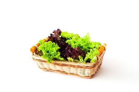 Fresh lettuce leaves in a wicker basket on a white isolated background. Close-up, copy space