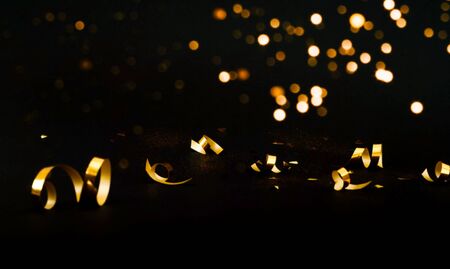 Black background with golden sparkles. Concept for festive background or for project. Blurred effect. Close-up, copy spaceの写真素材