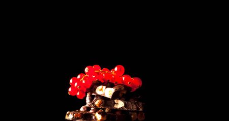 Pieces of chocolate with almonds and red berries on black background. Copy space, close-upの写真素材