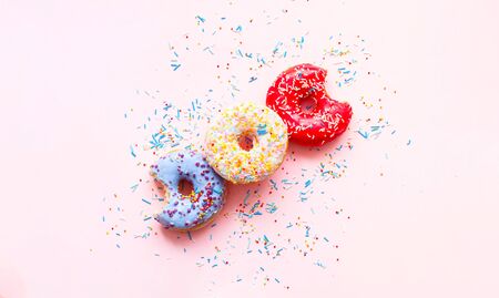Colored donuts with colorful sprinkles on pink background. Close-upの写真素材