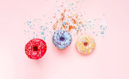 Colored donuts with colorful sprinkles on pink background. Concept colorful breakfast. Copy space, close upの写真素材