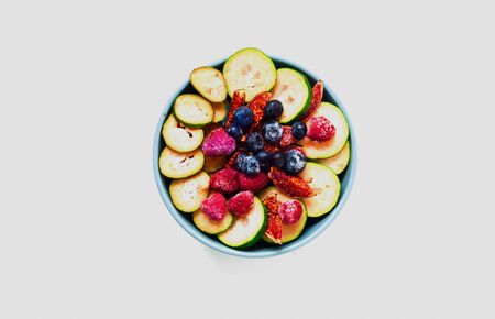 Fruit salad of wild berries and exotic fruits on white isolated background. The concept of a healthy diet, zero waste. Close up, copy space.の写真素材