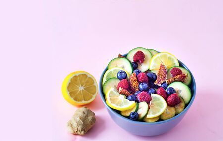Fruit salad of wild berries and exotic fruits on pink background. The concept of a healthy diet,...