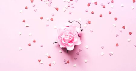 Festive concept with alarm clock and roses flower on pink background .Valentines Day. Close-up, copy spaceの写真素材