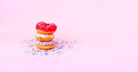 Colored donuts with colorful sprinkles on pink background. Copy space, close-upの写真素材