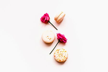 Festive composition. Multicolored macaroons and rose flowers on isolated white background. Close-up, copy spaceの写真素材