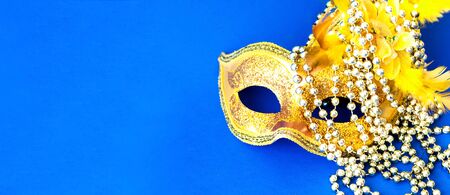 Carnival mask on blue background with silver beads. Mardi Gras concept. Copy space, close-up