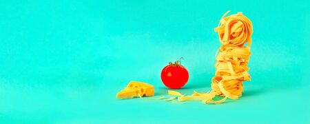 Homemade fettuccine noodles with ingredients on turquoise background. Italian traditional cuisineの写真素材