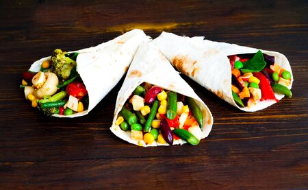 Mexican tortilla with vegetable and mushroom fillings on wooden background. Cooking delicious food at home. Close-up, creative copy spaceの写真素材