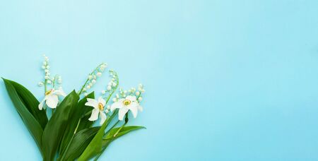 Creative blue background mit lilies of the valley and daffodils . Summer equinox or hello summer concept. Close-up, copy spaceの写真素材