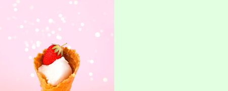 Ice cream in waffle cone with fresh strawberries on pink background. National ice cream day 19 july concept. Close-up, creative copy space.の写真素材