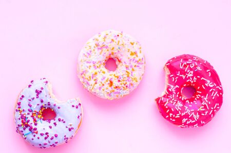 Colored donuts with colorful sprinkles on pink background. National Pink Day or Doughnut day concept.の写真素材