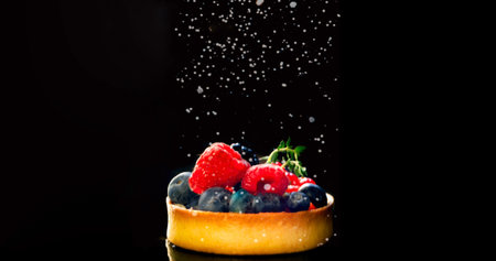 Cupcake with berries sprinkled with icing sugar on black background.Food concept.Close-up. Copy...