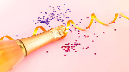 Champagne bottle with confetti on pink background. Blurred effect. Creative space for Christmas design.の写真素材