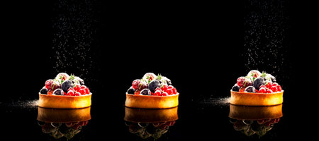 Cupcakes with berries sprinkled with icing sugar on dark background. Conceptual Food.Close-up. Copy spaceの写真素材
