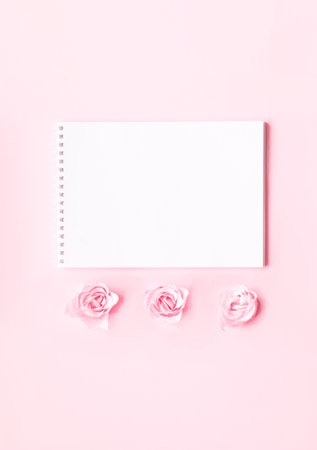 Festive concept with notebook and rosebuds on pink background. Valentines Day. Template mock up of greeting card or text design. Close-up, creative copy spaceの写真素材