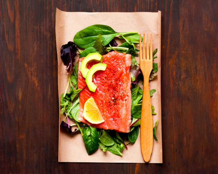 Salmon fillets with spinach and avocado in sustainable packaging on wooden background. Concept health-conscious. Close-up, copy space. Top view.の写真素材