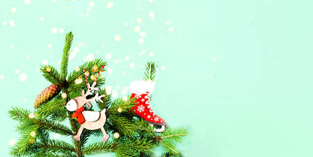 Fir branch with cones and and wooden toys on green background. Christmas decorations. Creative copy...