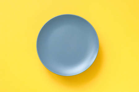 Gray plate for food on yellow background. Trending colors of 2021. Creative copy spaceの写真素材