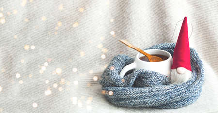 Christmas toy Santa Claus and white cup with tea on knitted texture. Christmas greeting card. Creative copy space. Close-upの写真素材