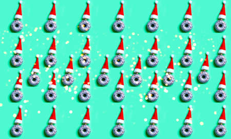 Pattern of Silver donut with sequins and red santa claus hat on green background. Festive. Design for festive wrapping paper. Christmas moodの写真素材