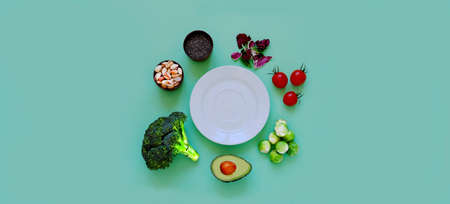 Ingredients for proper nutrition and empty white plate on green background. The concept of healthy...