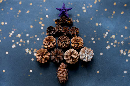 Christmas tree made of pine cones on a blue background with sparkles. New year Color Trends, Attention-grabbing Palettes 2023 year. DIY jewelry.の写真素材