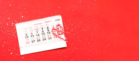 Calendar with marked date December 25 with candy cane heart. Preparing for Christmas, Advent calendar on red background. Creative copy space for seasonal projects.の写真素材