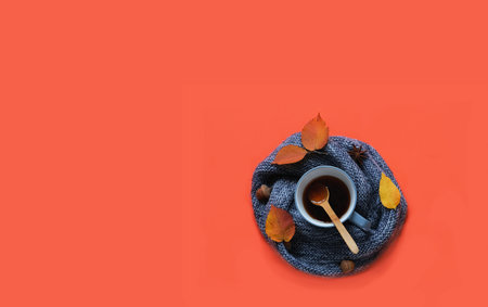 Blue cup with tea and autumn leaves on knitted texture on apricot background. Autumn mood. Bold hues for basis designs and seasonal projects. Close-upの写真素材