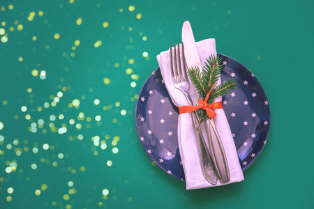 Cutlery and restaurant napkin on Christmas plate on green background. Christmas or New Year design for the holiday.の写真素材