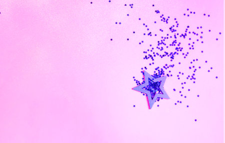 Purple sparkles and decorative star on pink background. The concept of the season holidays. Creative copy space for design.の写真素材