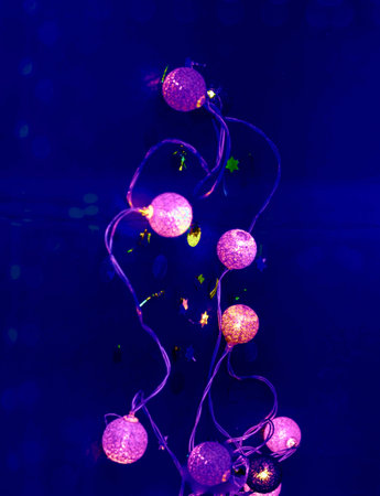 Festive garlands with purple lights on dark background. Christmas decor and home decoration for the...