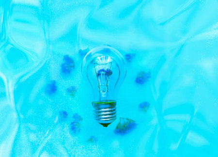 Turned off lightbulb on blue background with hologram. The concept of energy saving or environmental...