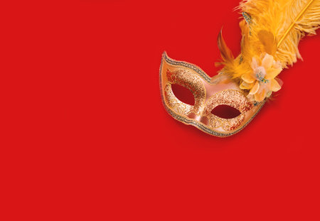 Golden Carnival mask against background in shades of red. Mardi Gras concept or New Years decoration. Festive background. Close-upの写真素材