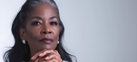 Portrait of Middle aged black woman on gray background. Advertising anti-aging cosmetics. International Womens Day. Copy space. Bannerの素材