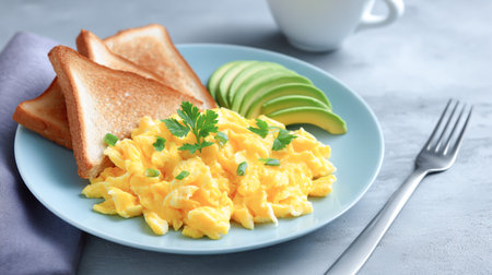 Fluffy scrambled eggs are beautifully arranged on a plate with toasted bread and avocado slices, creating a colorful and appetizing breakfast presentationの素材
