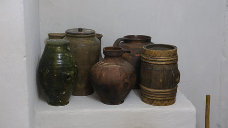 Traditional pottery jars and containers arranged on a white shelf, highlighting unique shapes and...