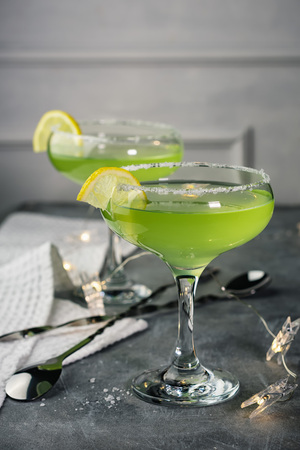 Two margarita cocktails with salt and lemon on a gray stone bar table.の写真素材