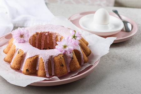 Vanilla cake with raisins and berry cream, decorated with pink sakura flowers.