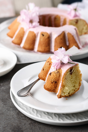 Vanilla cake with raisins and berry cream, decorated with pink sakura flowers.