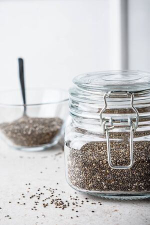 Chia seeds in a glass jar on a light kitchen table.の写真素材