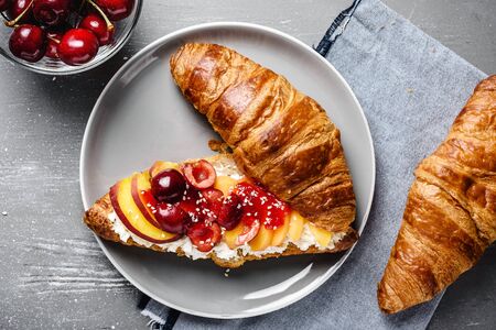 Croissant with cottage cheese and fresh peach, apricot and cherry. Healthy breakfast.の写真素材
