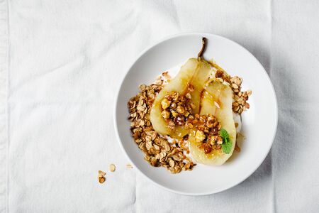 Poached pear with yogurt, walnuts and oat granola.の写真素材