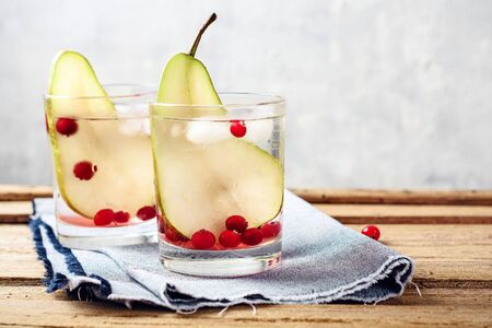 Glass of refreshing drink with pear and cranberries on a wooden table.の写真素材