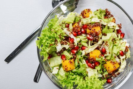 Salad with kale, pumpkin, red quinoa and pomegranate in a glass bowl.の写真素材
